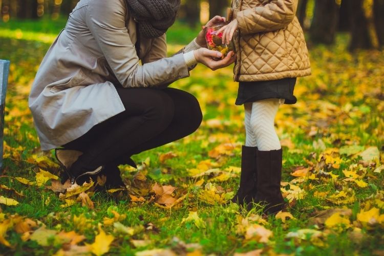 mere qui tient la main de son enfant qui tient un trésor de la nature en forêt