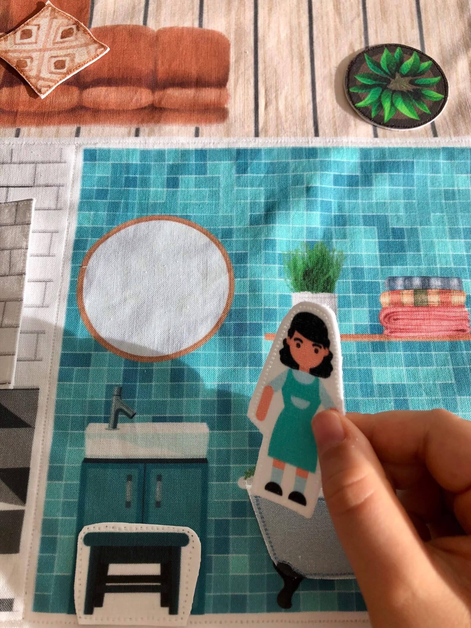 mains d'enfants qui jouent avec personnages dans salle de bain d'un tapis maison de poupées en tissu