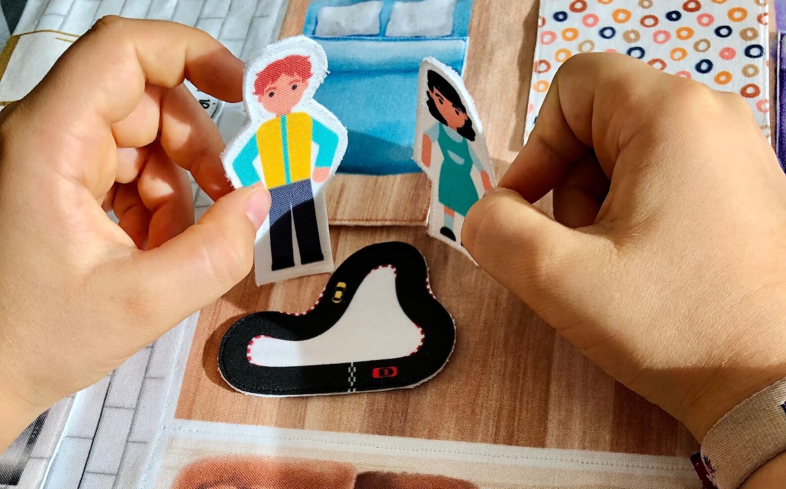mains d'enfants qui jouent avec personnages d'un tapis maison de poupées en tissu